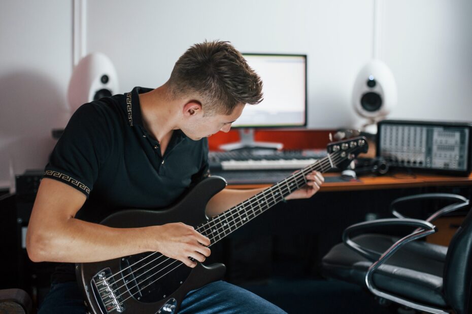 Young musician records bass guitar indoors in the studio